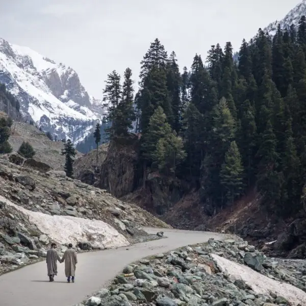 2 men holding hands walking in Kashmir, traditional outfits