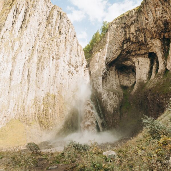 A high, stormy waterfall flowing down the massive rocks of Djily-su. A journey through the mountain