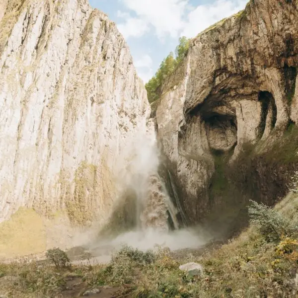 A high, stormy waterfall flowing down the massive rocks of Djily-su. A journey through the mountain