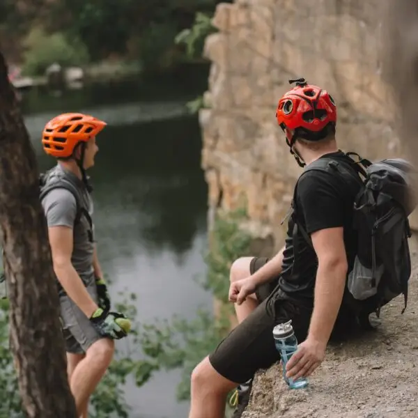 young tourists in helmets relaxing on rocky cliff after ride