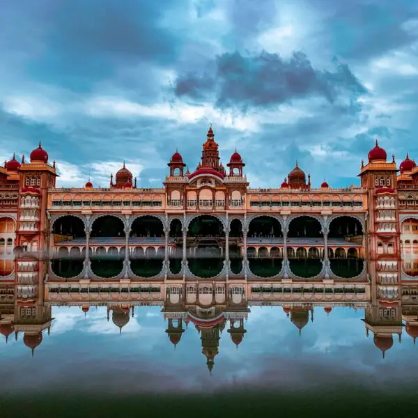 Beautiful Mysore palace of India under cloudy sky making mirror reflection in water