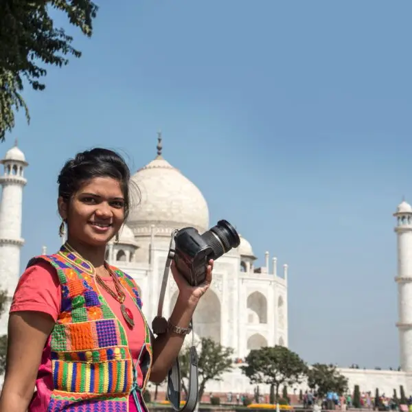 Young woman tourist taking photos of Taj Mahal,